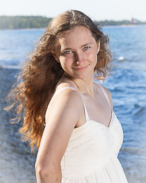 A senior portrait of a girl with water behind her