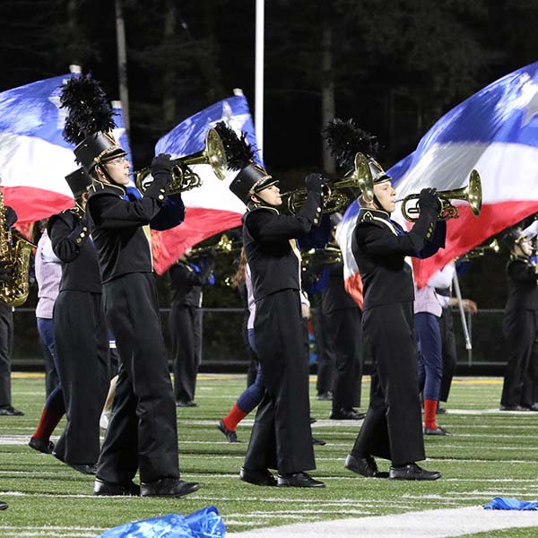 Members of the Hastings Marching Band in uniform performing with red white and blue flags