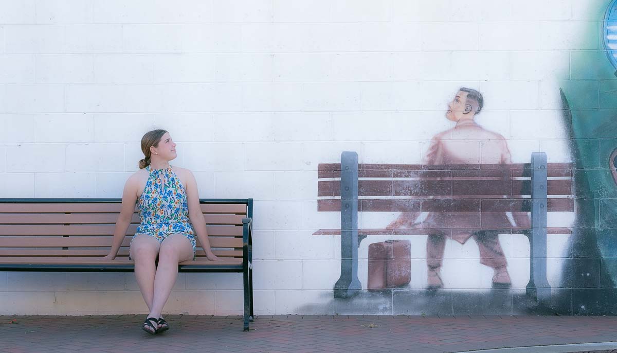 Senior girl sitting on bench looking at a mural