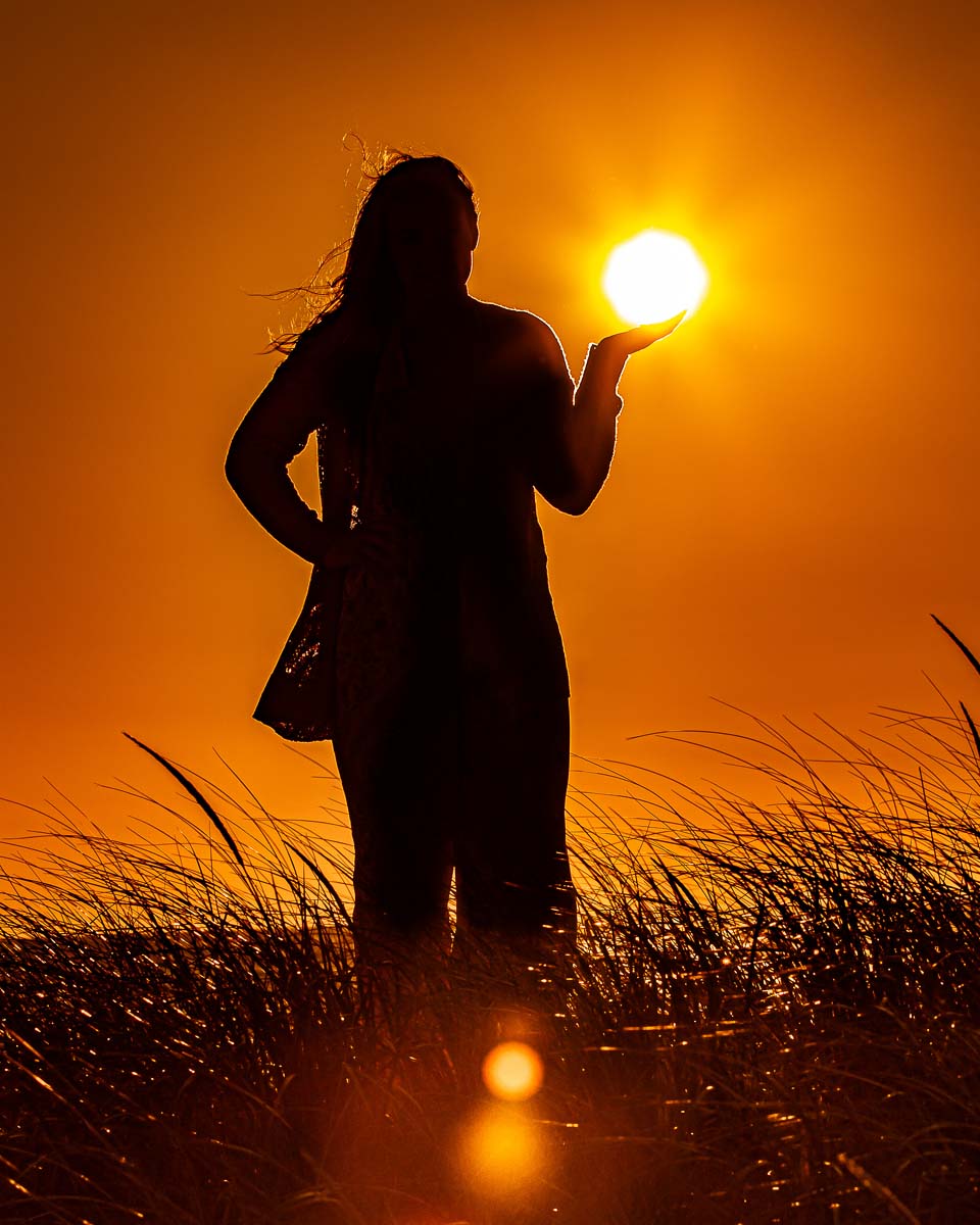 Darkened picture of a girl with the sun above her hand