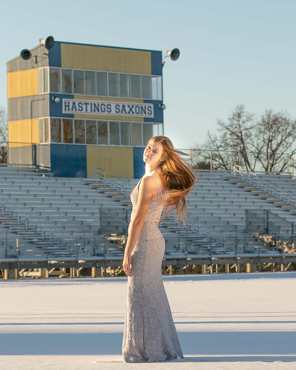 Senior in a dress standing in front of the Hastings football stadium