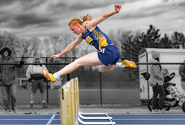 Girl jumping over a hurdle with a gray background